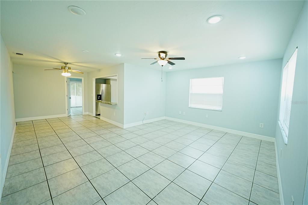 An open-concept living area features light blue walls, large floor tiles, and two ceiling fans — 1882 RITA STREET, SARASOTA, FL