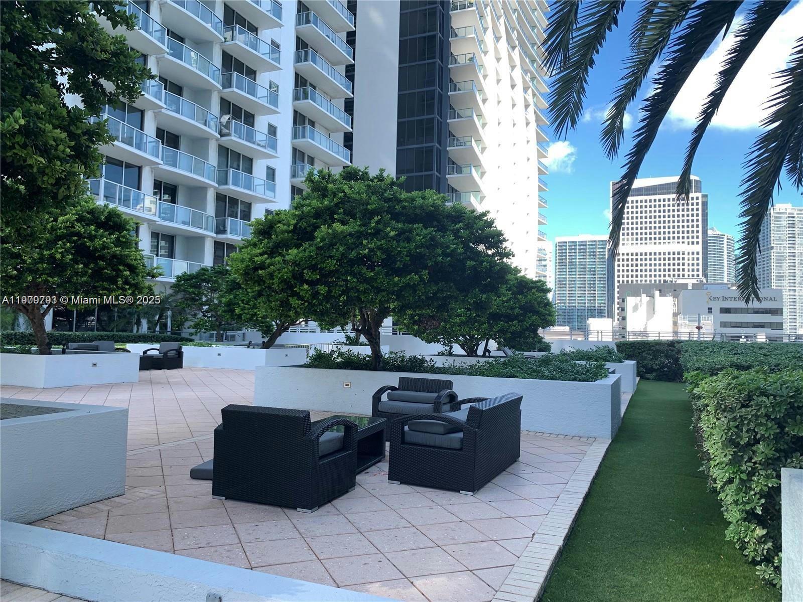 An outdoor terrace features patio furniture, planters with trees, and views of surrounding high-rise buildings — 1060 Brickell Ave # 1701, Miami FL 33131, MIAMI, FL