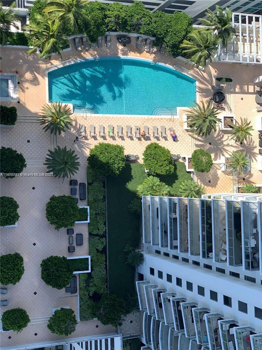 An aerial view shows a swimming pool, lounge chairs, palm trees, and a building exterior — 1060 Brickell Ave # 1701, Miami FL 33131, MIAMI, FL