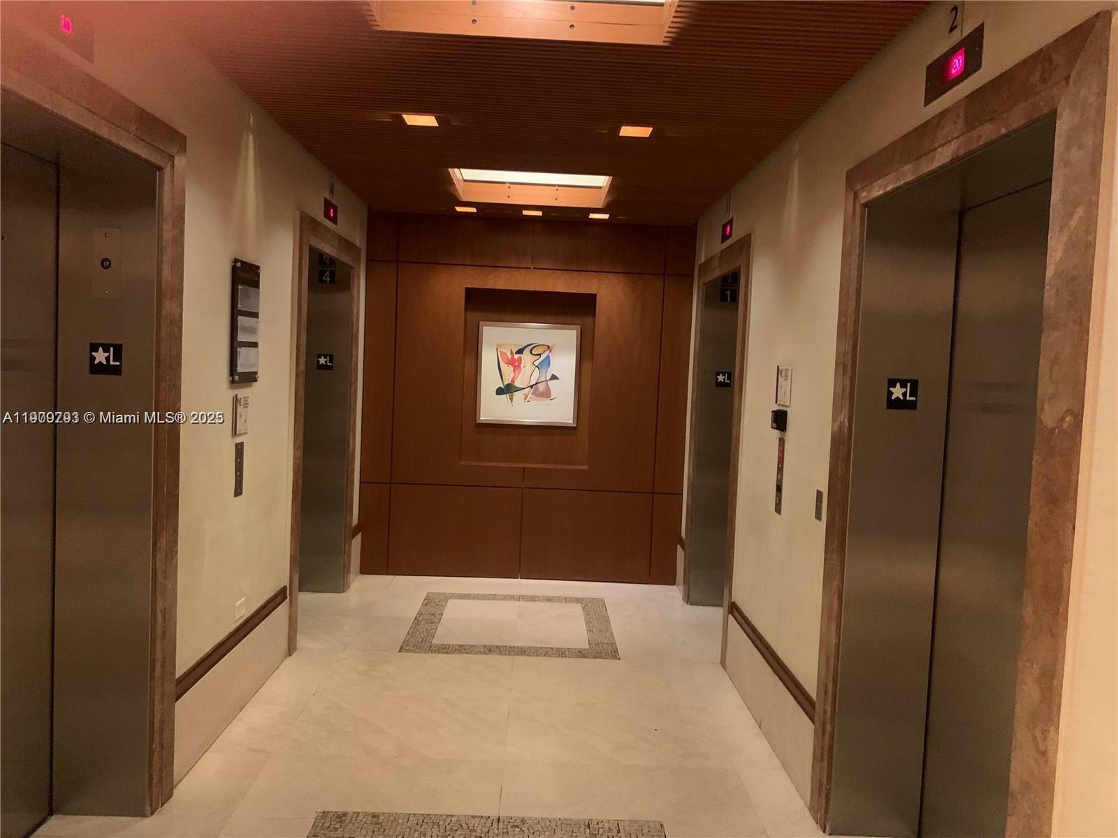 An elevator lobby features four stainless steel doors, wood paneling, and a central framed artwork — 1060 Brickell Ave # 1701, Miami FL 33131, MIAMI, FL