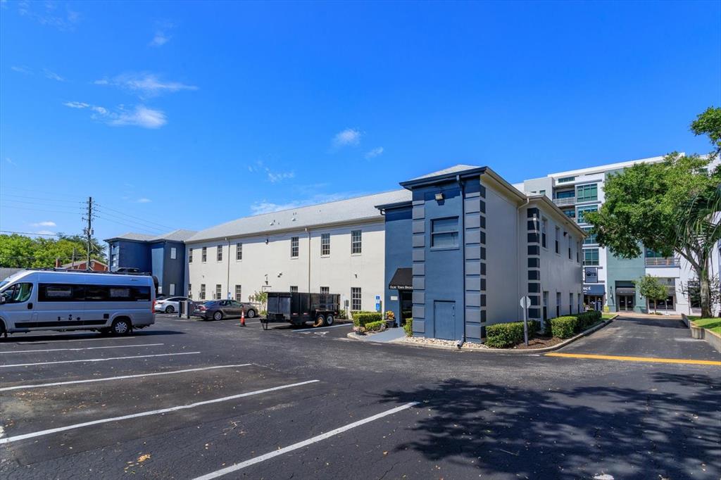 A multi-story commercial building with a blue facade and parking lot under a blue sky — 11 N SUMMERLIN AVENUE UNIT 100, ORLANDO, FL