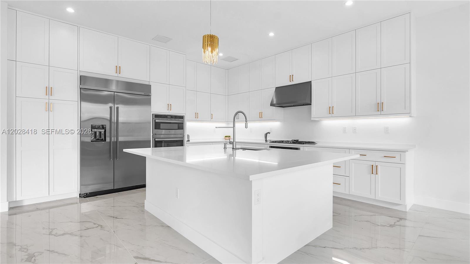 A modern white kitchen features a large center island, stainless steel appliances, and marble flooring — 20284 Bandon Dunes Rd, Boca Raton FL 33434, BOCA RATON, FL