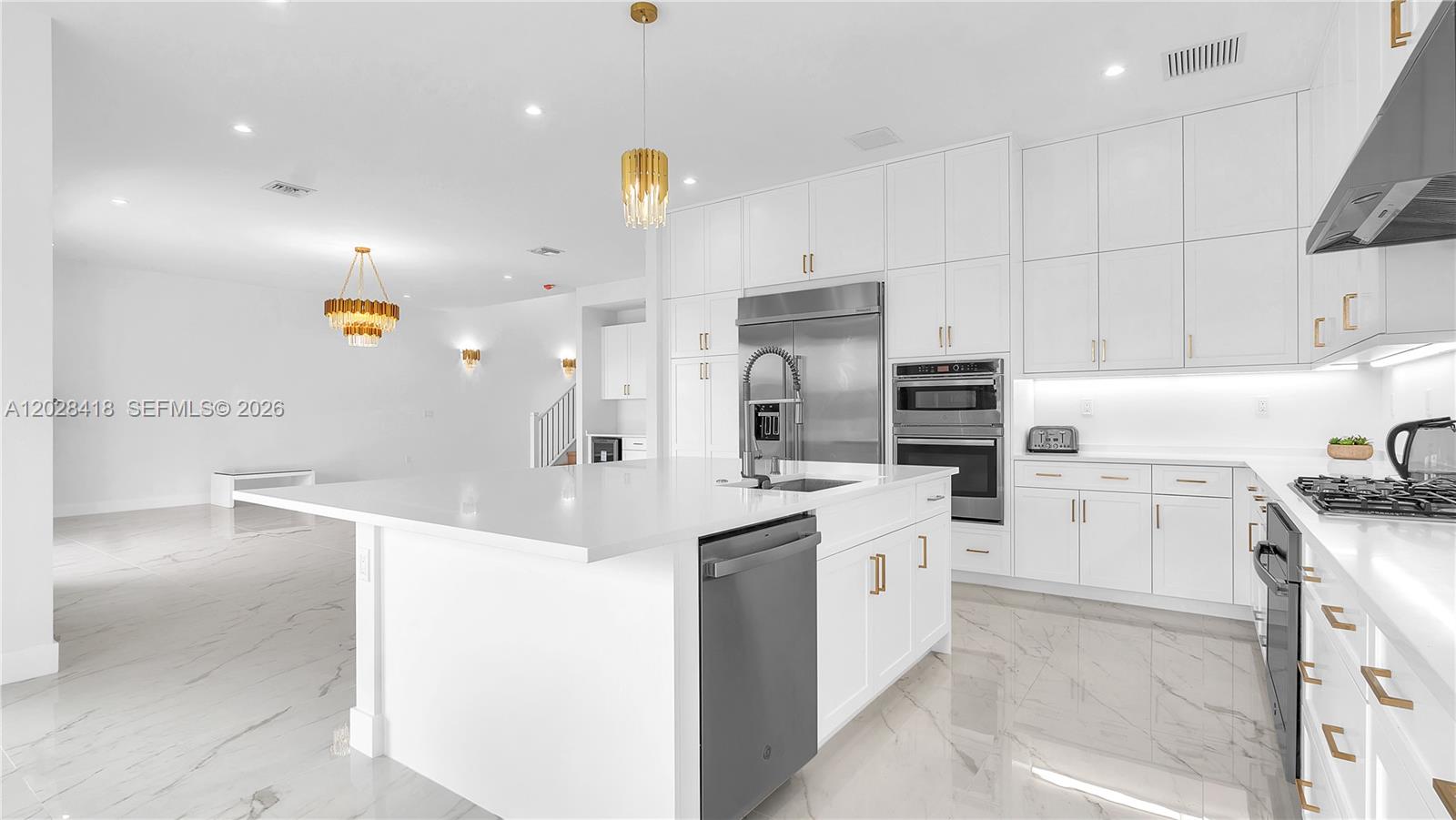 A modern white kitchen features a large island, stainless steel appliances, and marble-style flooring — 20284 Bandon Dunes Rd, Boca Raton FL 33434, BOCA RATON, FL