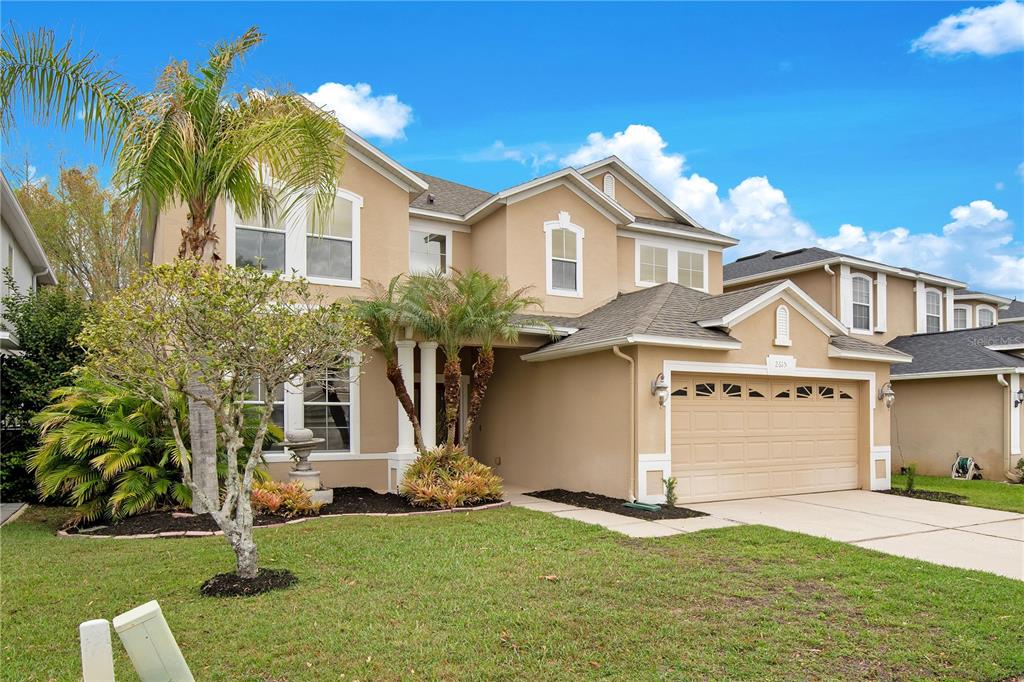A two-story tan stucco house with a two-car garage and a front palm tree — 2615 LAKEMOOR DRIVE, ORLANDO, FL