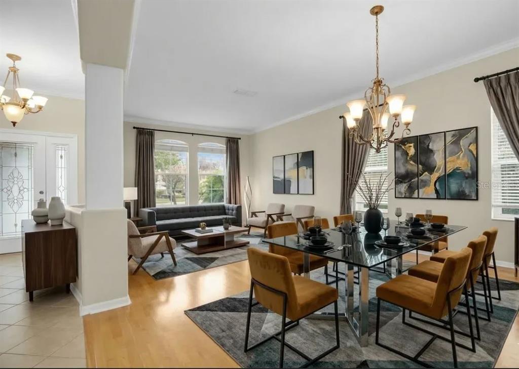 A dining area with a glass table and gold chairs sits next to a living room — 2615 LAKEMOOR DRIVE, ORLANDO, FL