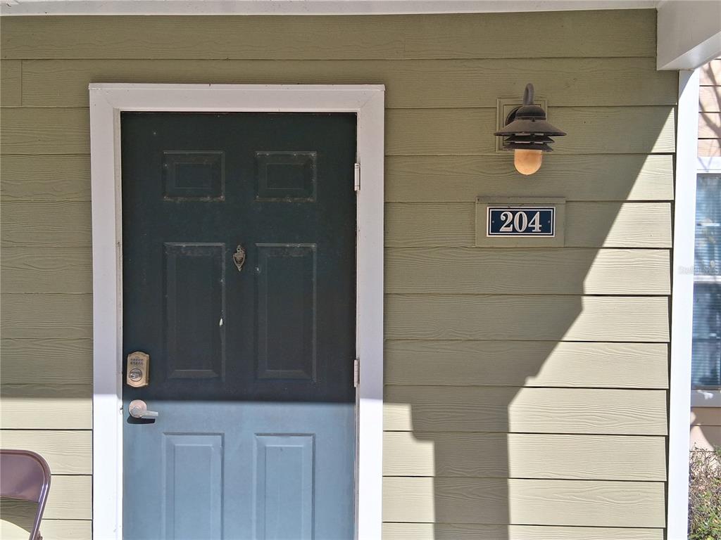 A dark green front door with a keypad lock is labeled with the number 204 — 2763 LIGHTHOUSE COVE ROAD UNIT 6-204, ORANGE CITY, FL