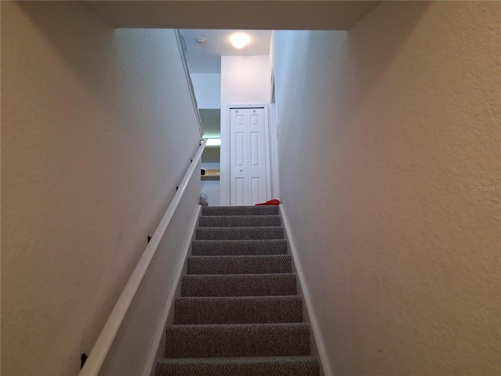 A carpeted staircase leads upward to a landing with a white door — 2763 LIGHTHOUSE COVE ROAD UNIT 6-204, ORANGE CITY, FL