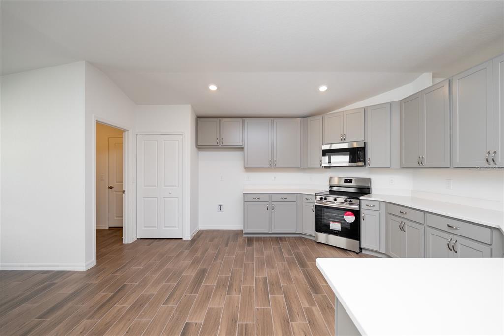 A kitchen features light gray cabinets, stainless steel appliances, and wood-look tile flooring — 213 HARPER ESTATES CIRCLE, LAKE WALES, FL