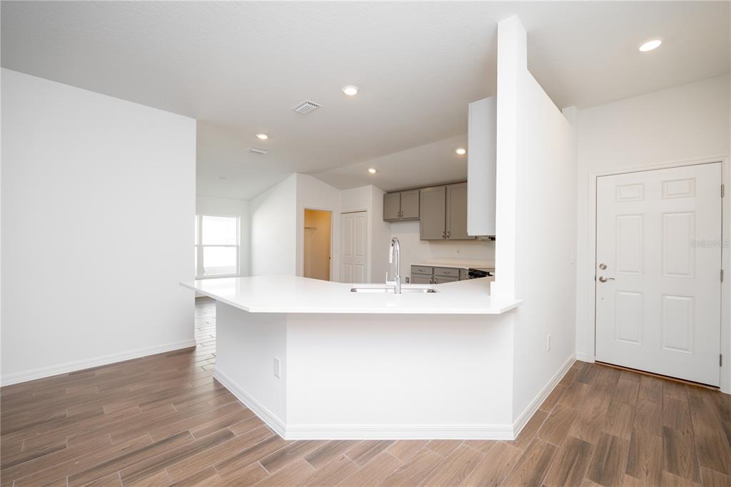 A kitchen with a white peninsula countertop, gray cabinets, and wood-look tile flooring — 213 HARPER ESTATES CIRCLE, LAKE WALES, FL