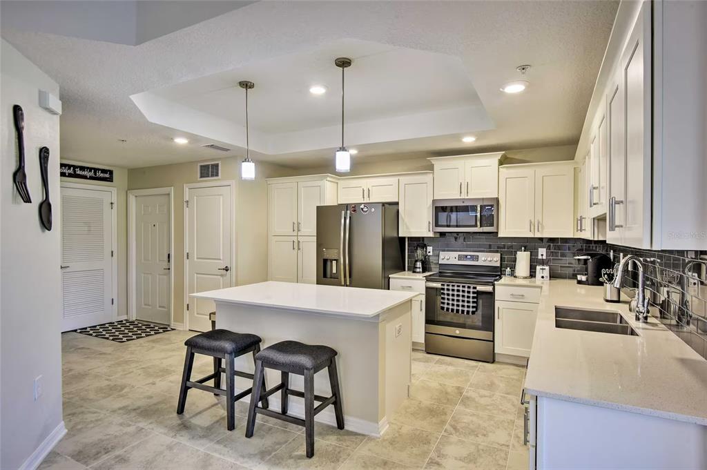 A kitchen with white cabinets, a central island, stainless steel appliances, and tile flooring — 3111 PARADOX CIRCLE UNIT 108, KISSIMMEE, FL