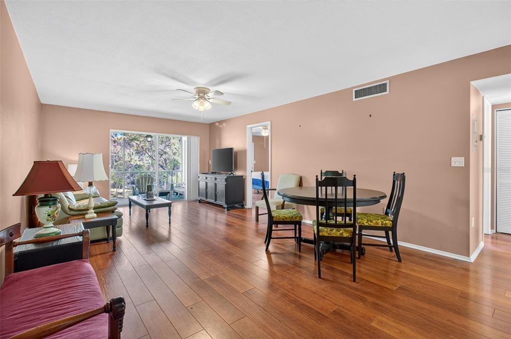 A living and dining area with hardwood floors, a ceiling fan, and a sliding glass door — 208 CYPRESS COURT, OLDSMAR, FL