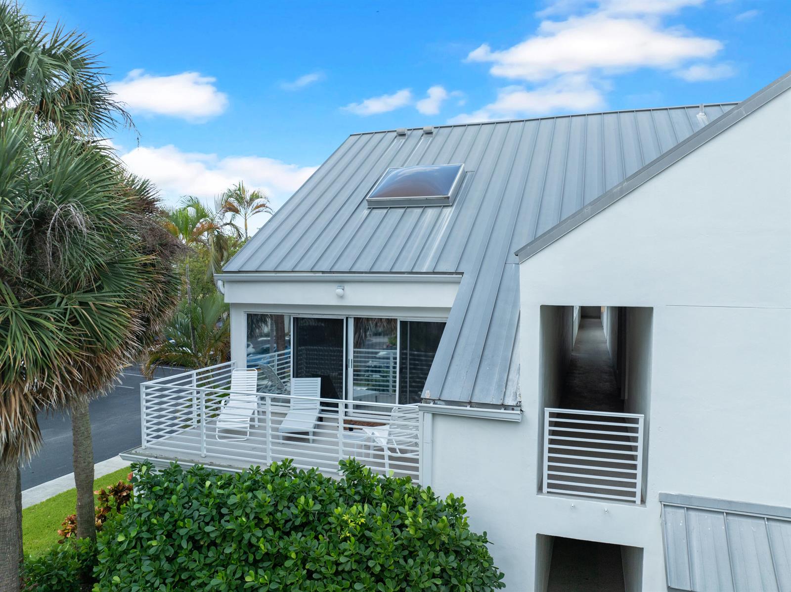 An exterior view of a white building with a metal roof, balcony, and skylight — 1605 S Us Highway 1 # 215, Jupiter FL 33477, JUPITER, FL