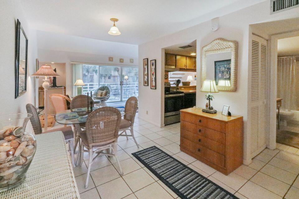 A dining area with wicker chairs and a glass table leads to a kitchen — 1605 S Us Highway 1 # 215, Jupiter FL 33477, JUPITER, FL