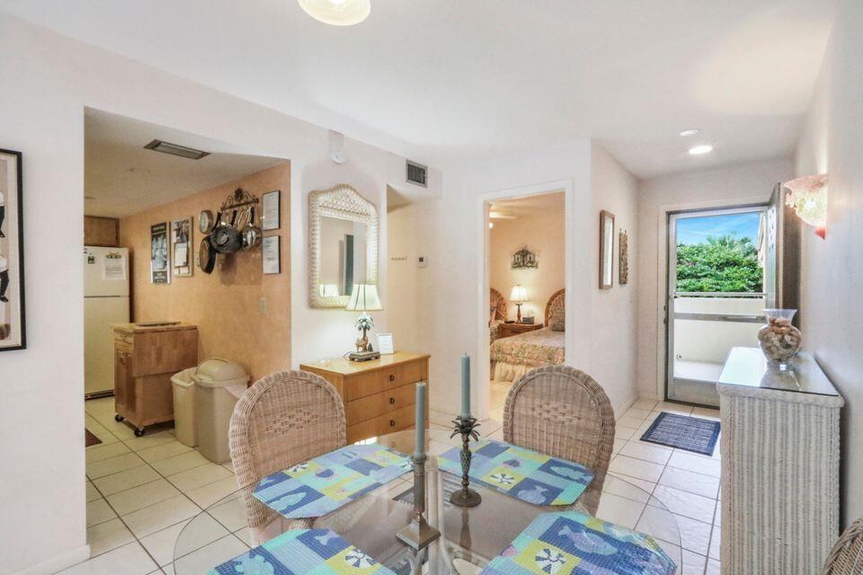 A dining area with a glass table and wicker chairs leads to a kitchen and bedroom — 1605 S Us Highway 1 # 215, Jupiter FL 33477, JUPITER, FL