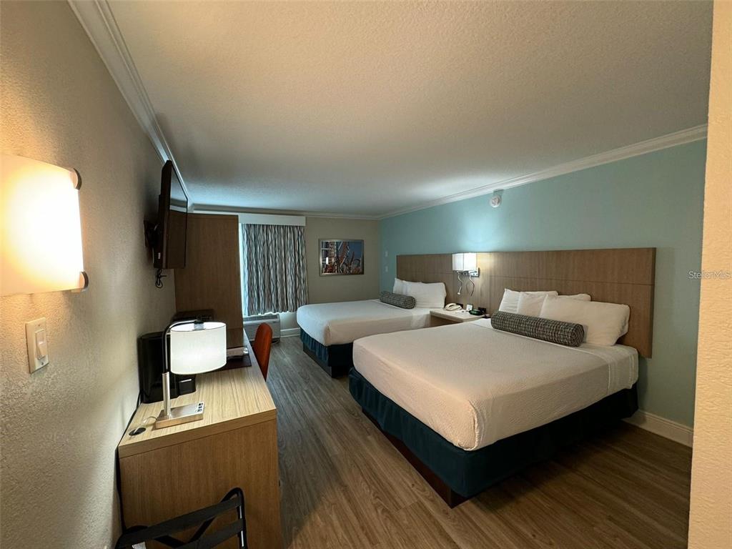 A hotel room features two beds, a desk, and light-colored wood-look flooring — 3000 MAINGATE LANE UNIT 520, KISSIMMEE, FL