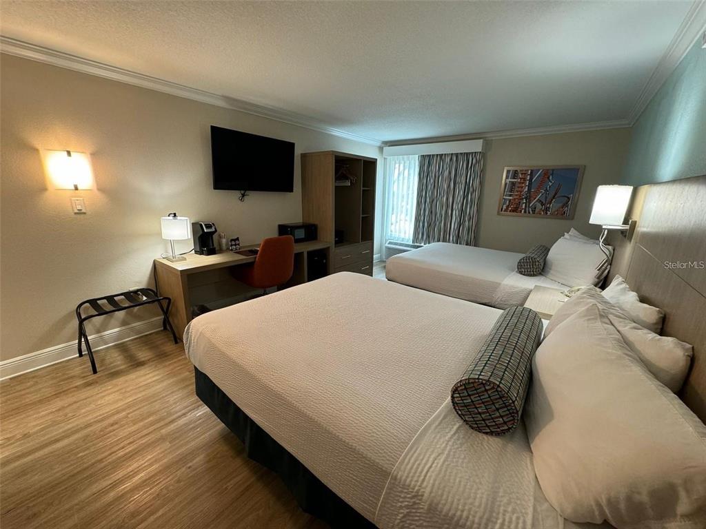 A hotel room features two beds, a desk with a chair, and a wooden wardrobe — 3000 MAINGATE LANE UNIT 520, KISSIMMEE, FL