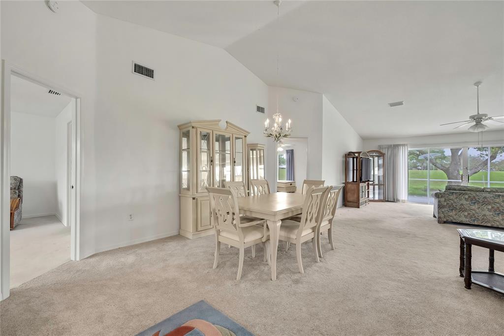 A dining area with a light-colored table and chairs sits on beige carpeted flooring — 11203 SUN TREE ROAD, HUDSON, FL