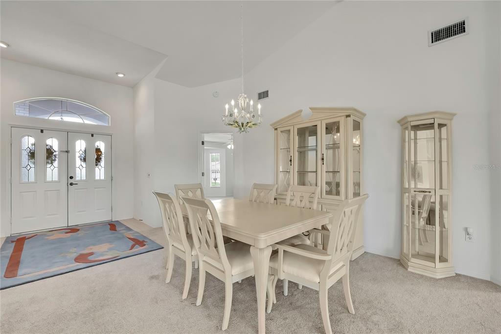 A dining room features a light-colored table and chairs, a hutch, and a chandelier — 11203 SUN TREE ROAD, HUDSON, FL