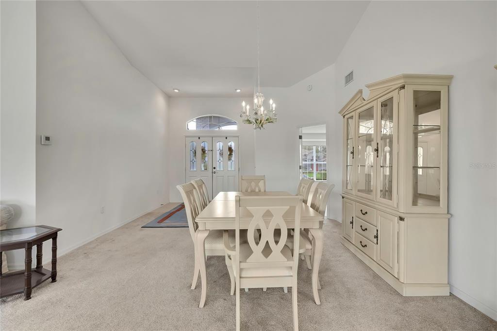 A dining room features a light-colored table and chairs, a matching hutch, and carpeted floors — 11203 SUN TREE ROAD, HUDSON, FL