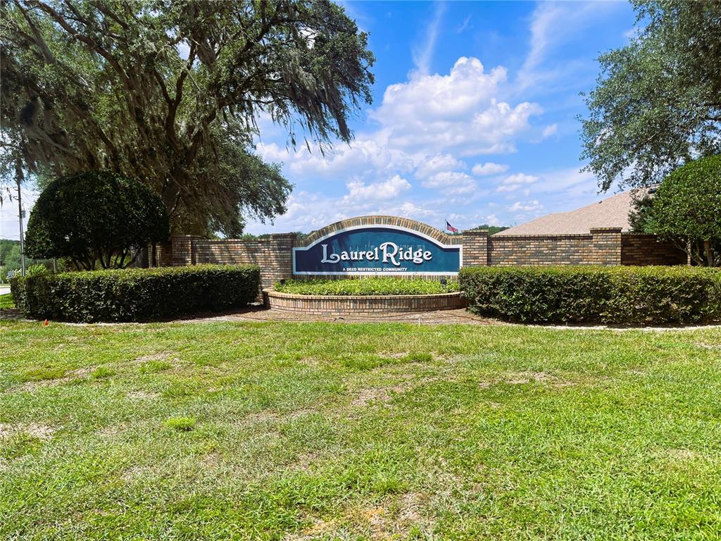 A brick entrance sign for Laurel Ridge community stands behind manicured hedges and a lawn — 521 W HILLWOOD PATH, BEVERLY HILLS, FL