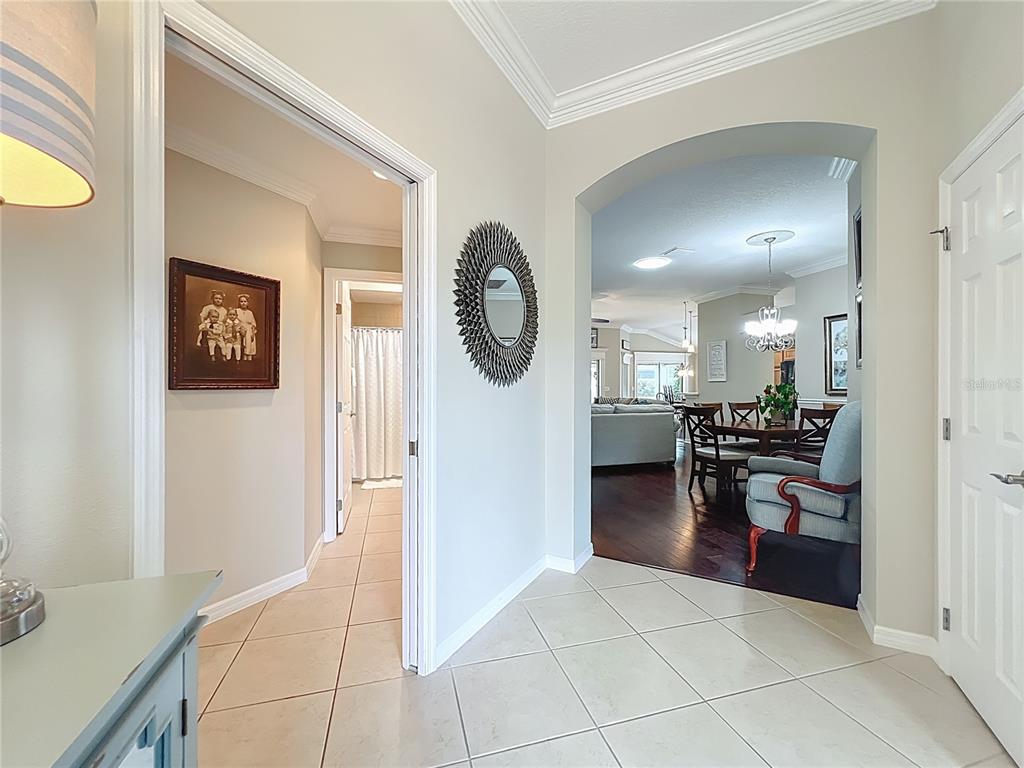 A tiled entryway leads to a dining area with hardwood floors and an arched opening — 2875 RAIN LILY LOOP, THE VILLAGES, FL