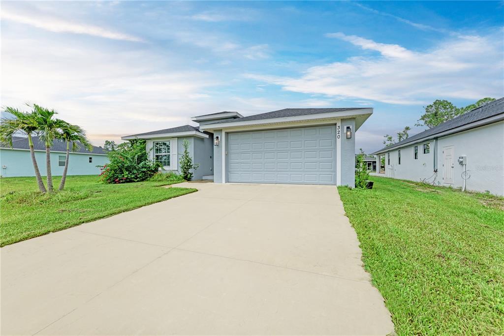 A single-story house with a gray garage, light-colored siding, and a concrete driveway — 320 ALBATROSS ROAD, ROTONDA WEST, FL