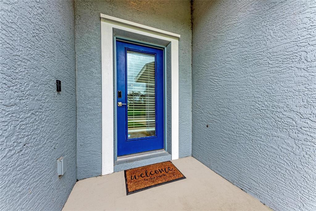 A blue front door with a glass insert sits in a textured gray stucco entryway — 320 ALBATROSS ROAD, ROTONDA WEST, FL
