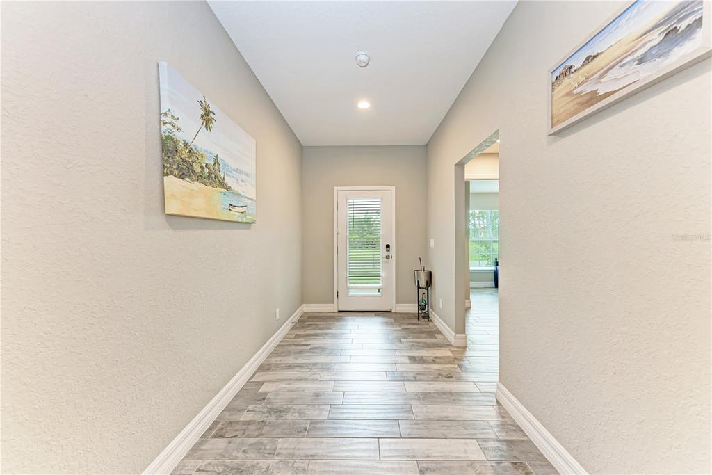 A bright entryway features light gray walls, wood-look tile flooring, and a glass-paneled exterior door — 320 ALBATROSS ROAD, ROTONDA WEST, FL