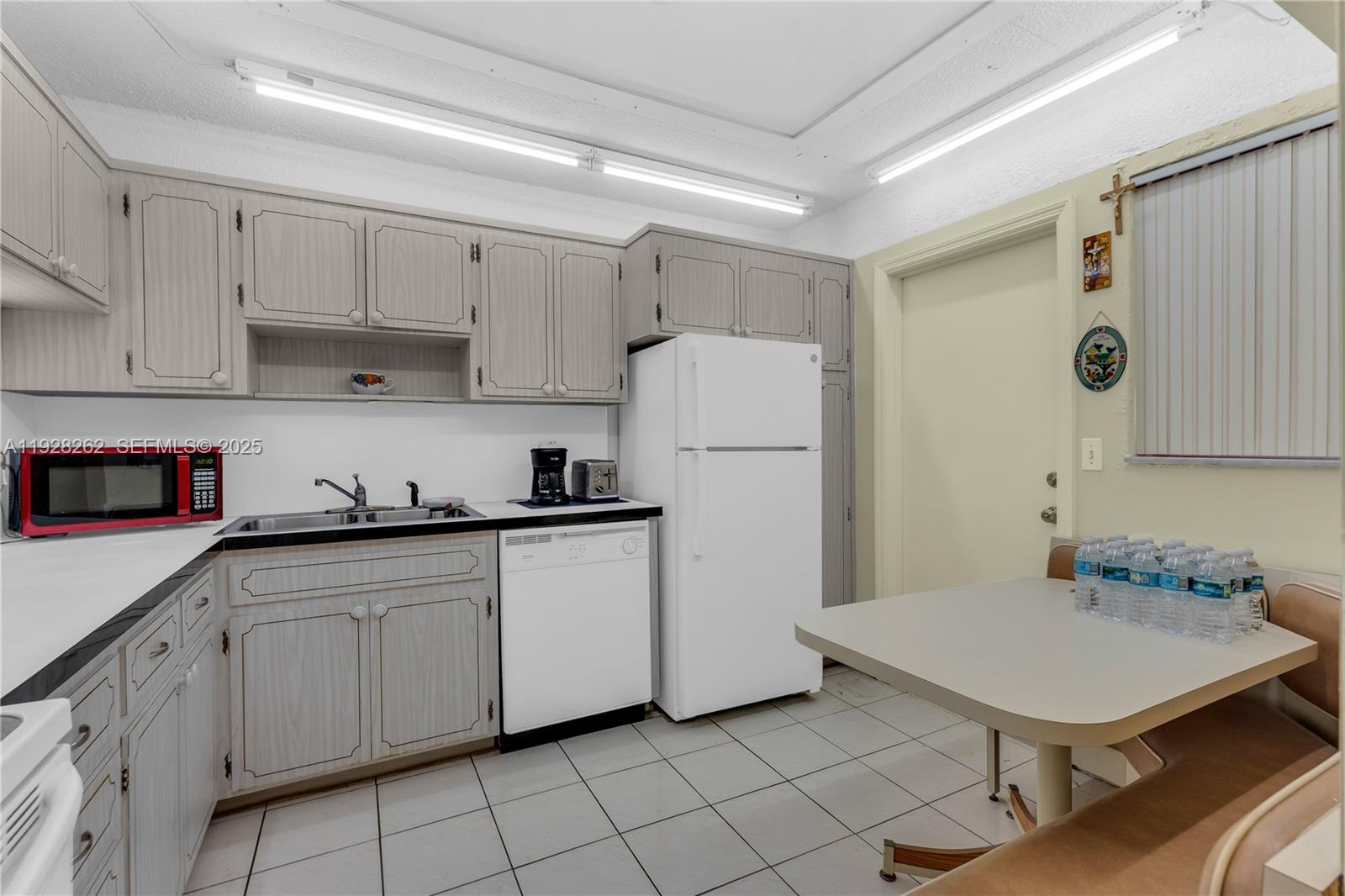A kitchen features light wood cabinets, white appliances, a tiled floor, and a dining nook — 215 SE 3rd Ave # 407B, Hallandale Beach FL 33009, HALLANDALE BEACH, FL