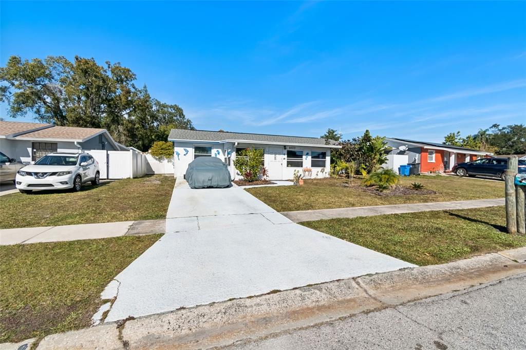 A single-story house with a white driveway, a covered car, and a white exterior — 6503 AMUNDSON COURT, TAMPA, FL