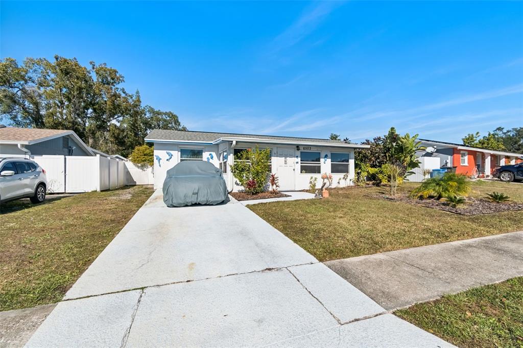 A single-story house with a white exterior, a concrete driveway, and a car under cover — 6503 AMUNDSON COURT, TAMPA, FL