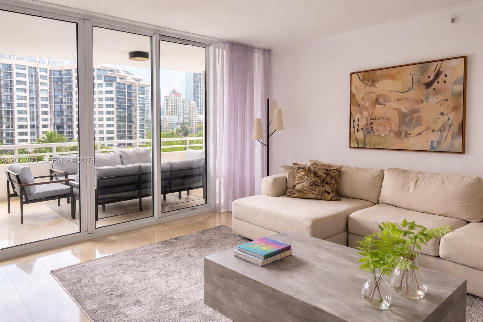 A living room features a beige sectional sofa, a gray coffee table, and a balcony view — 848 Brickell Key Dr # 905, Miami FL 33131, MIAMI, FL