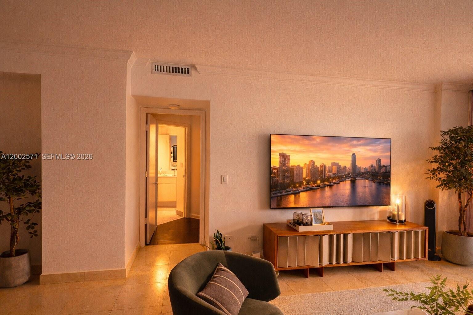 A living room features a wall-mounted television, a wooden media console, and two potted plants — 848 Brickell Key Dr # 905, Miami FL 33131, MIAMI, FL
