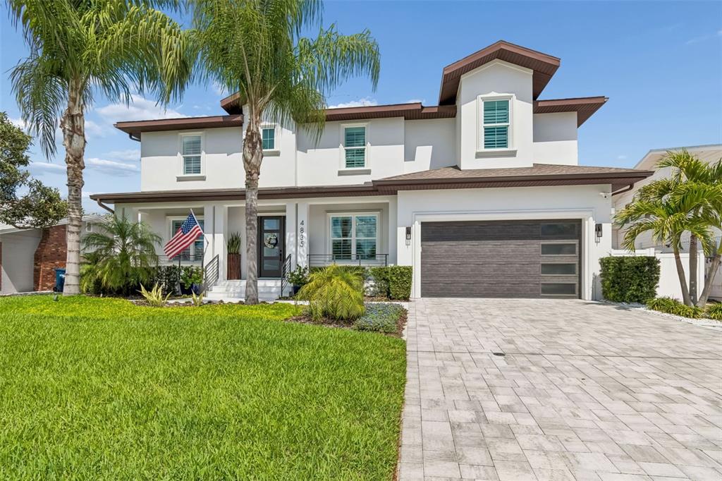 A two-story white house features a paved driveway, a garage, and palm trees — 4835 W BAY VILLA AVENUE, TAMPA, FL