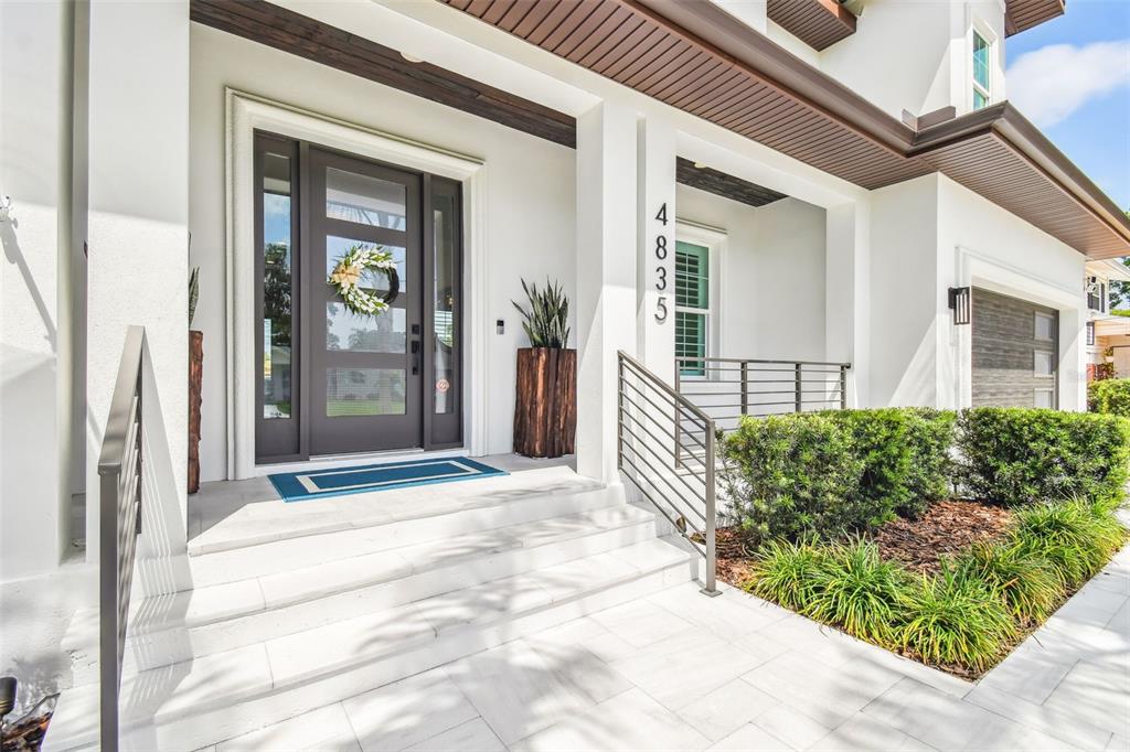 The front entrance features a dark door, white steps, and a modern metal railing — 4835 W BAY VILLA AVENUE, TAMPA, FL