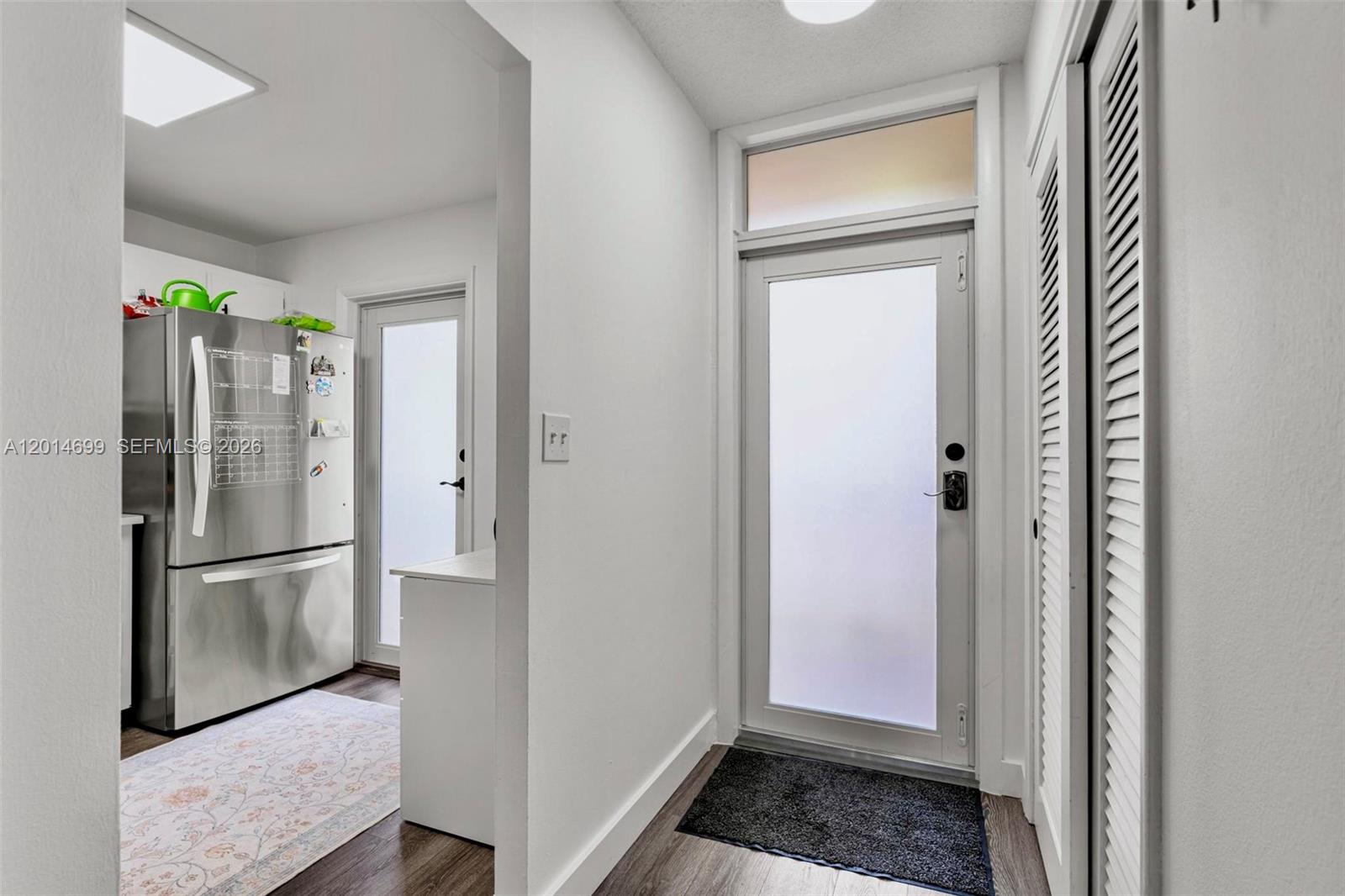 An entryway features a frosted glass door, a dark floor mat, and a nearby refrigerator — 609 NE 14th Ave # 405, Hallandale Beach FL 33009, HALLANDALE BEACH, FL