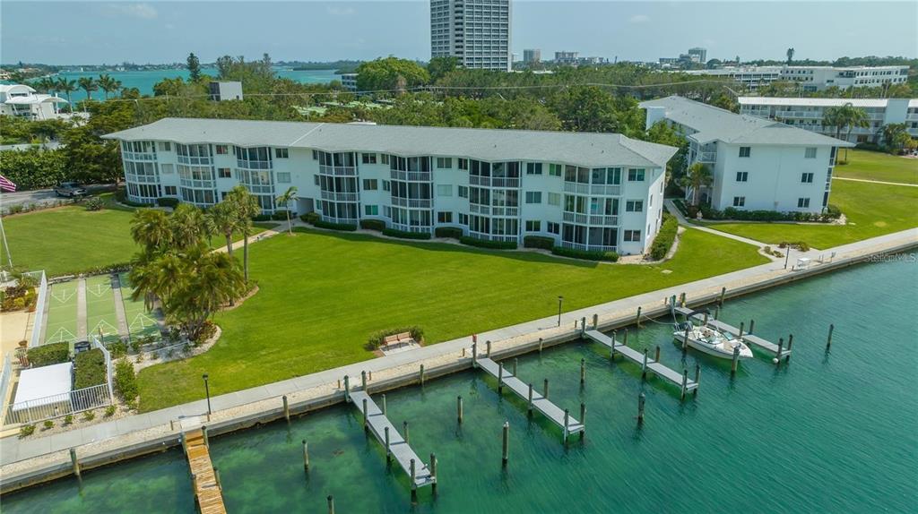 An aerial view of a multi-story apartment building with a lawn, boat docks, and water — 771 JOHN RINGLING BOULEVARD UNIT 3, SARASOTA, FL