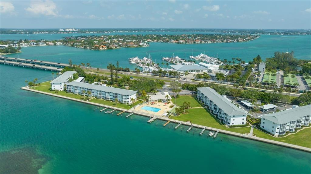 An aerial view of waterfront apartment buildings with a swimming pool and a nearby marina — 771 JOHN RINGLING BOULEVARD UNIT 3, SARASOTA, FL