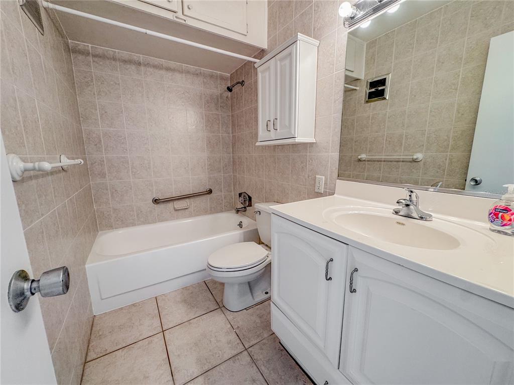 A bathroom features a tiled tub-shower combination, a white vanity, and a wall-mounted cabinet — 771 JOHN RINGLING BOULEVARD UNIT 3, SARASOTA, FL