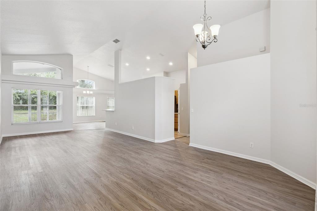 An open-concept living area features light gray walls, wood-look flooring, and a vaulted ceiling — 5483 GLEN OAK PLACE, SANFORD, FL