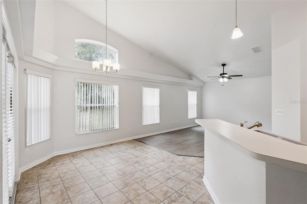 A dining area with tile flooring transitions to a living room with wood-look flooring — 5483 GLEN OAK PLACE, SANFORD, FL