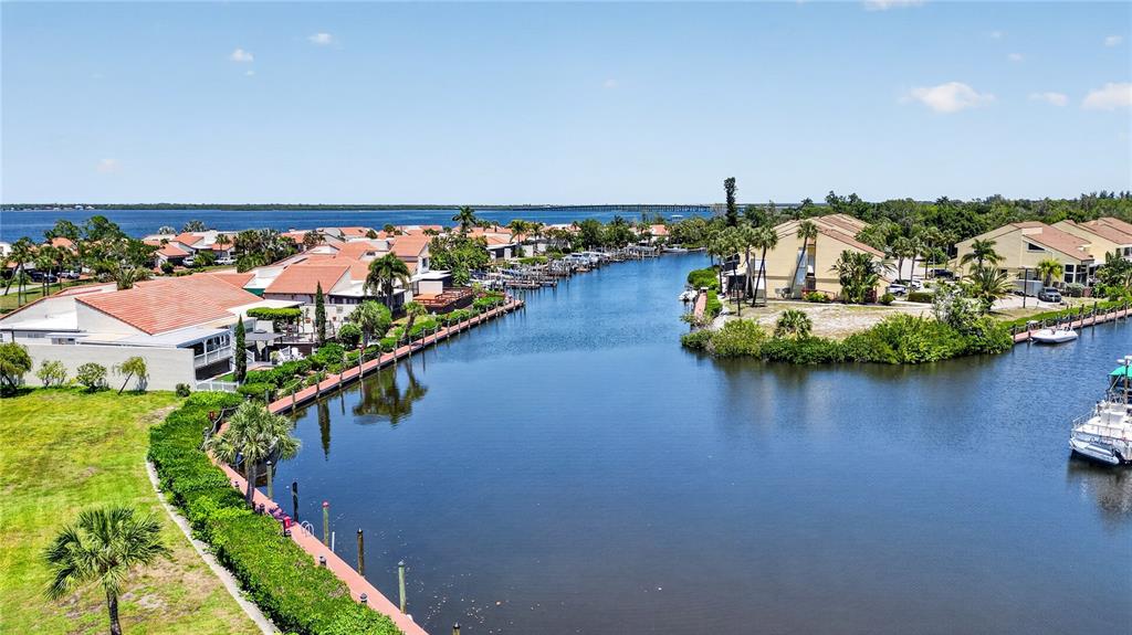 An aerial view shows a canal lined with residential buildings, docks, and boats — 25188 MARION AVENUE UNIT E208, PUNTA GORDA, FL