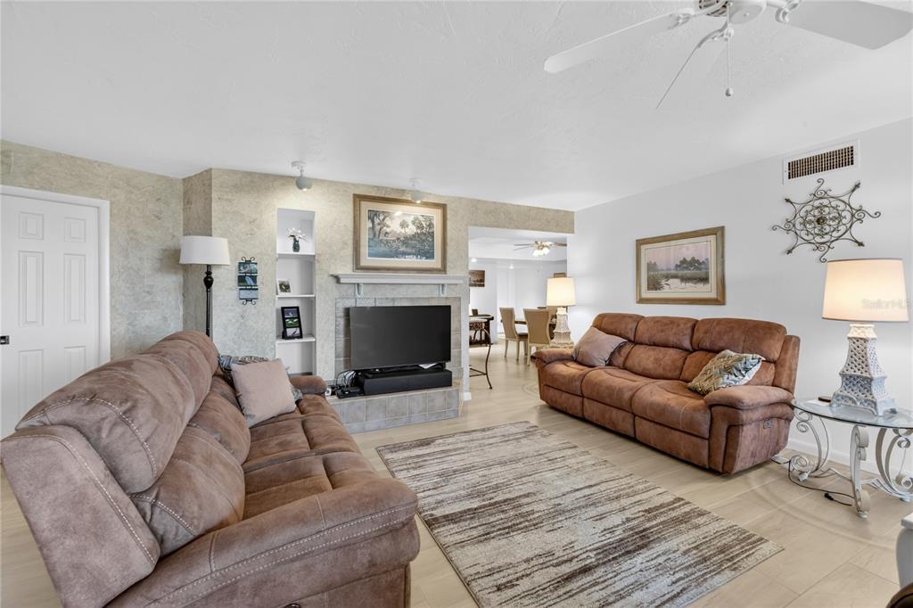 A living room features two brown sofas, a fireplace with a television, and light flooring — 25188 MARION AVENUE UNIT E208, PUNTA GORDA, FL