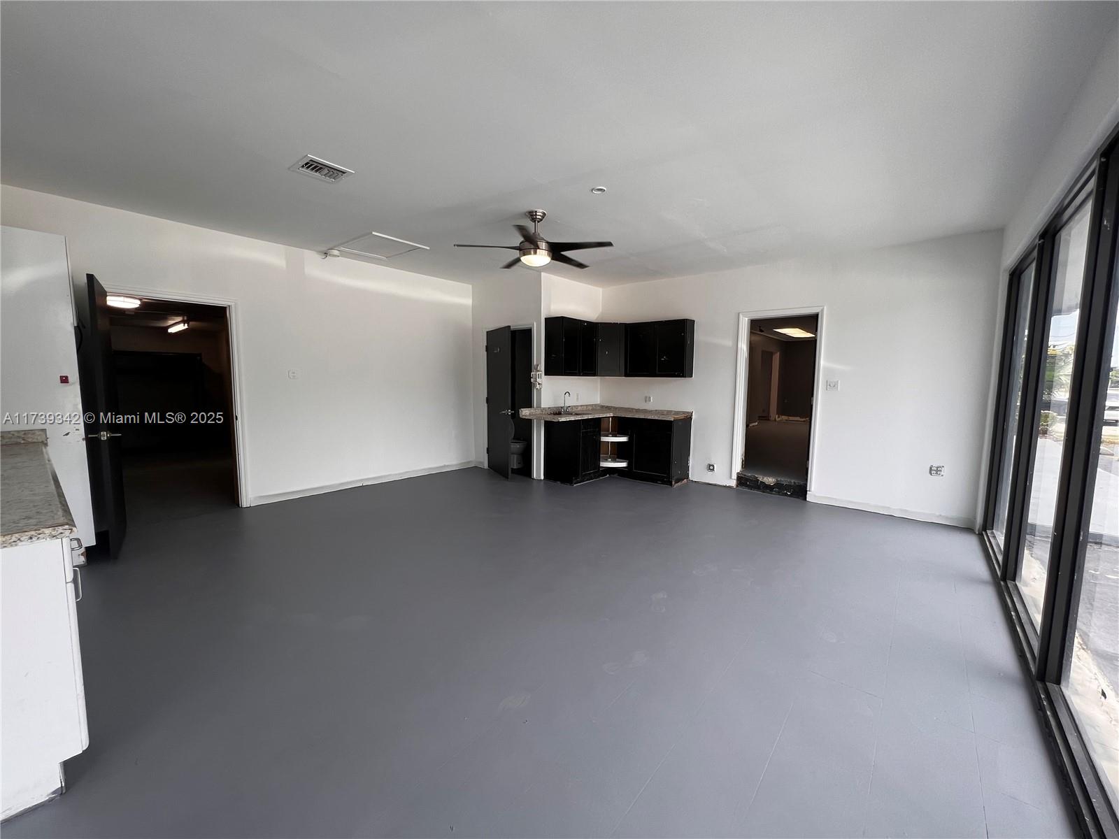 An open room features grey flooring, a small kitchenette with black cabinets, and sliding doors — 1100 S Dixie Hwy, Hollywood FL 33020, HOLLYWOOD, FL