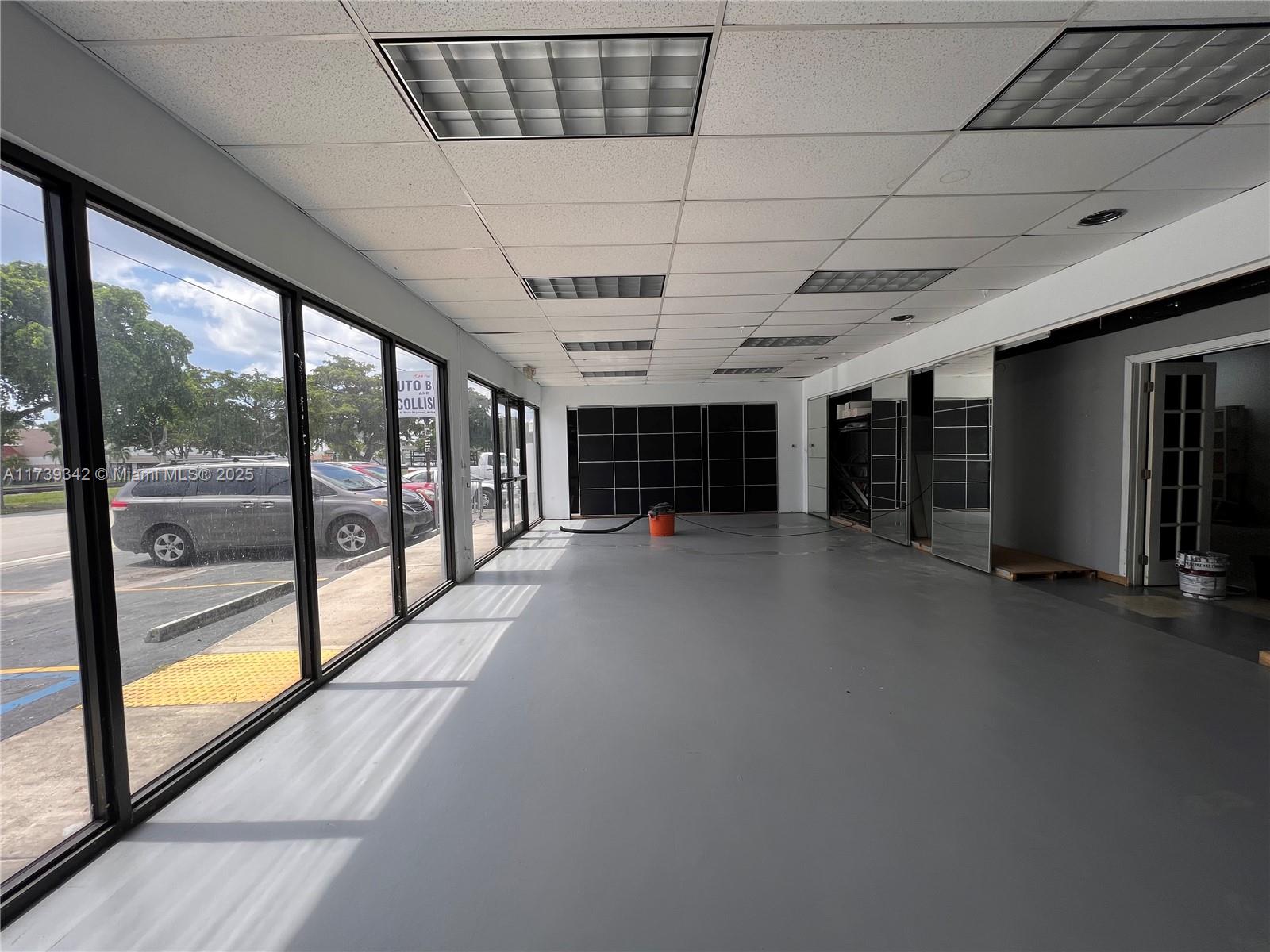 An empty commercial space features large windows, a gray floor, and a drop ceiling — 1100 S Dixie Hwy, Hollywood FL 33020, HOLLYWOOD, FL
