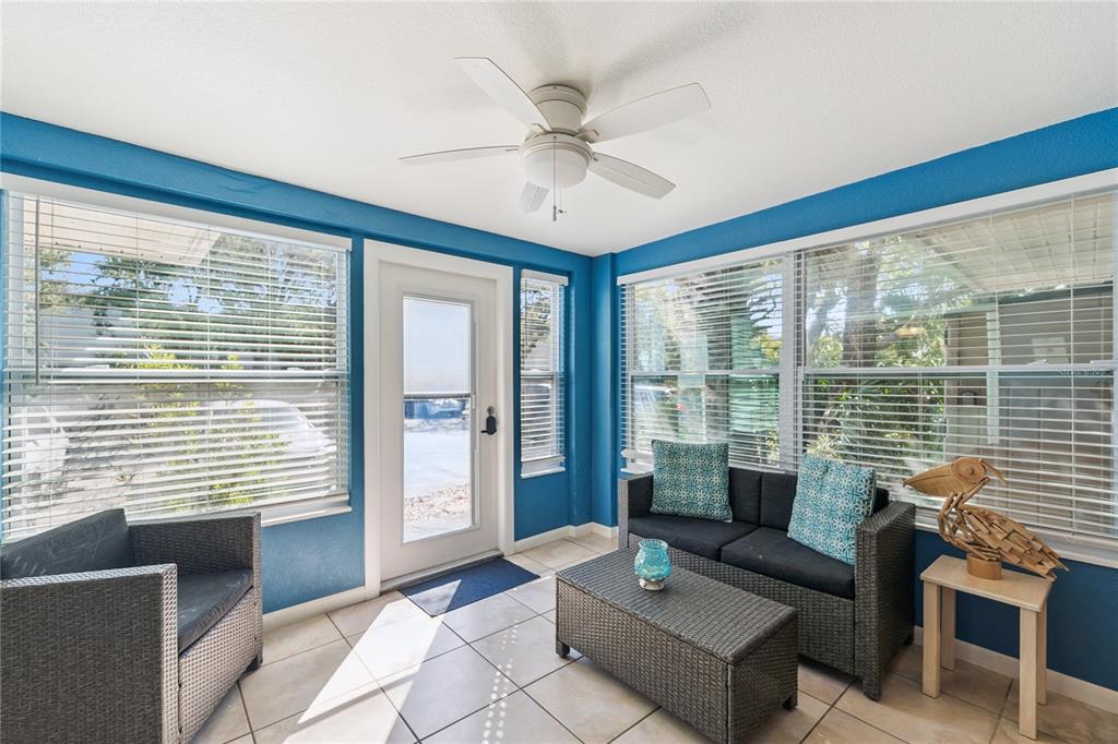 A sunroom with blue walls, tile flooring, a ceiling fan, and wicker-style patio furniture — 4150 S ATLANTIC AVENUE UNIT 121B, NEW SMYRNA BEACH, FL