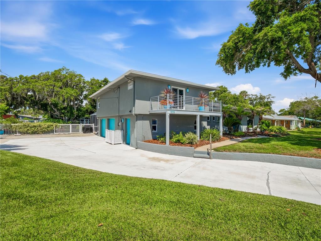 A two-story gray house features a second-floor balcony, a concrete driveway, and a grassy yard — 1508 S RIVERSIDE DRIVE, NEW SMYRNA BEACH, FL