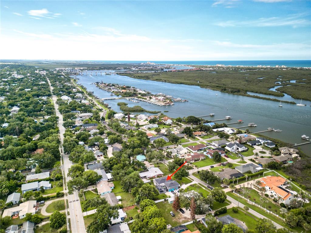 An aerial view shows a residential neighborhood near a coastal waterway with a red arrow — 1508 S RIVERSIDE DRIVE, NEW SMYRNA BEACH, FL