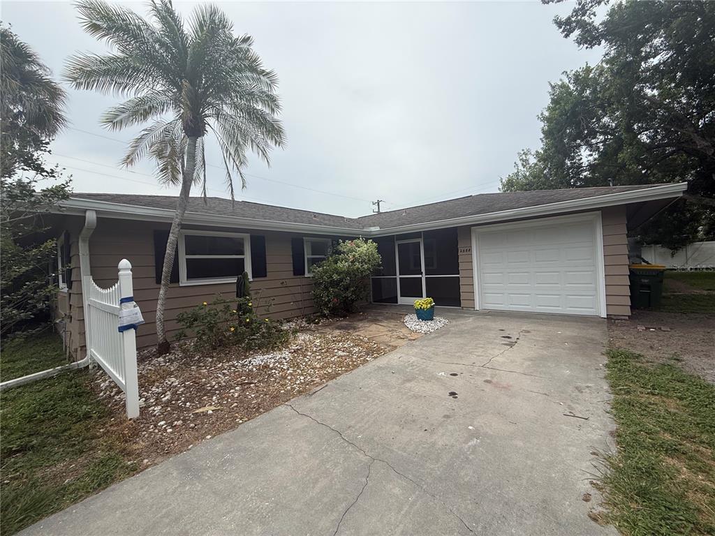 A single-story house with tan siding, a white garage door, and a palm tree — 2588 COLORADO STREET, SARASOTA, FL