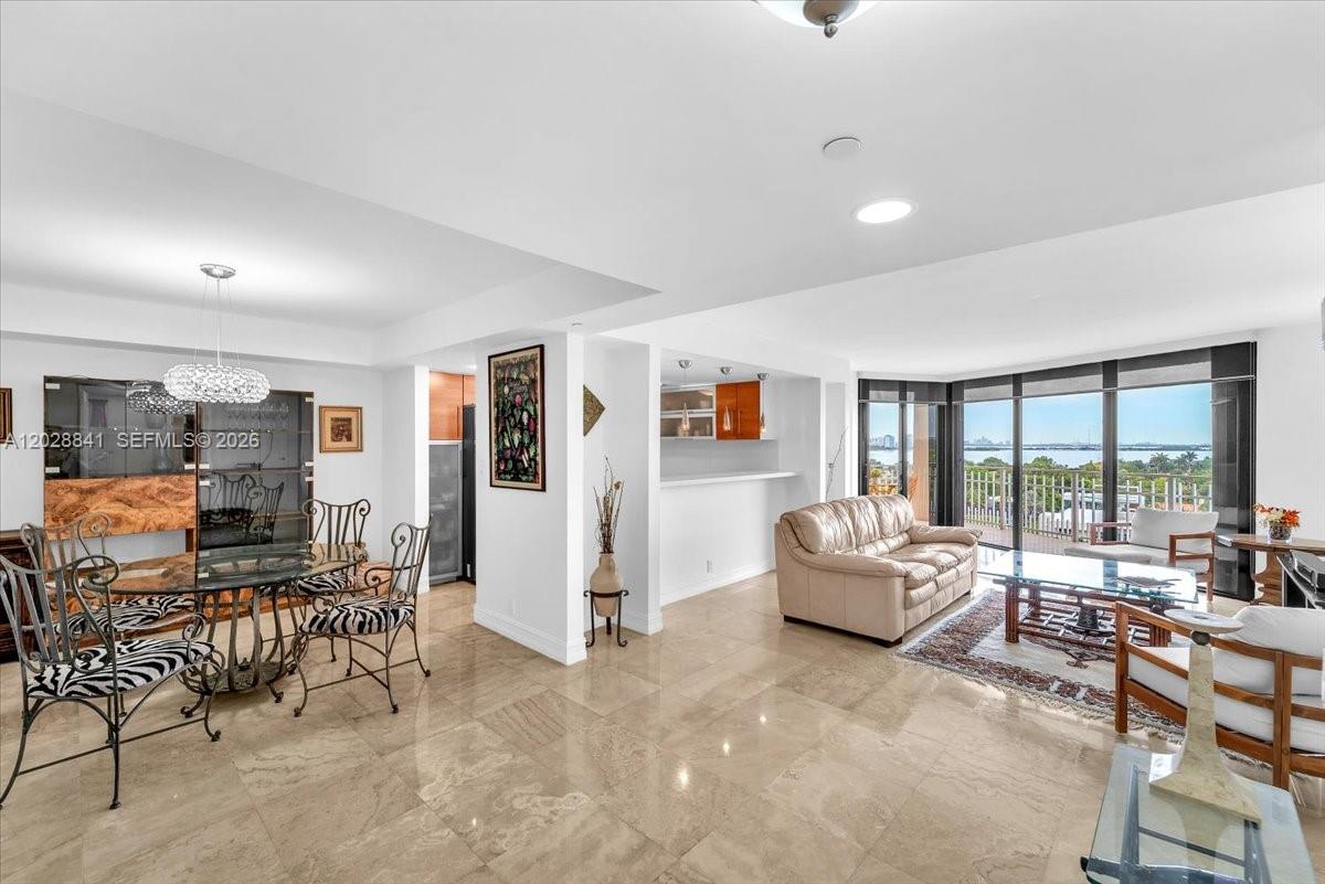 An open-concept living and dining area features tile flooring, a beige sofa, and floor-to-ceiling windows — 2000 Towerside Ter # 908, Miami FL 33138, MIAMI, FL